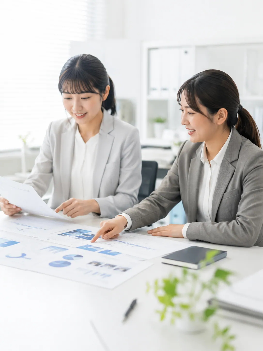 資料やグラフを見ながら市場分析・企画を検討する様子。